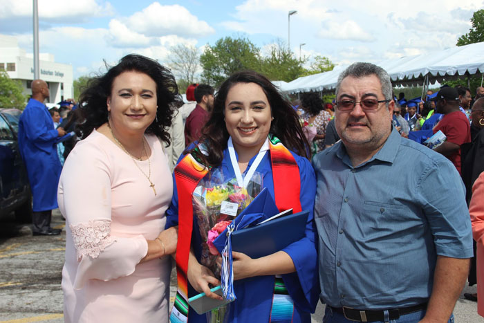 Diaz with parents after graduation in cap and gown